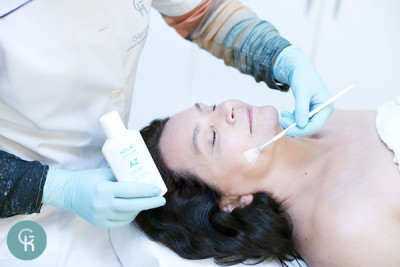 Kobieta podczas nakładania pędzelkiem przez kosmetologa peelingu chemicznego Azelac Peel